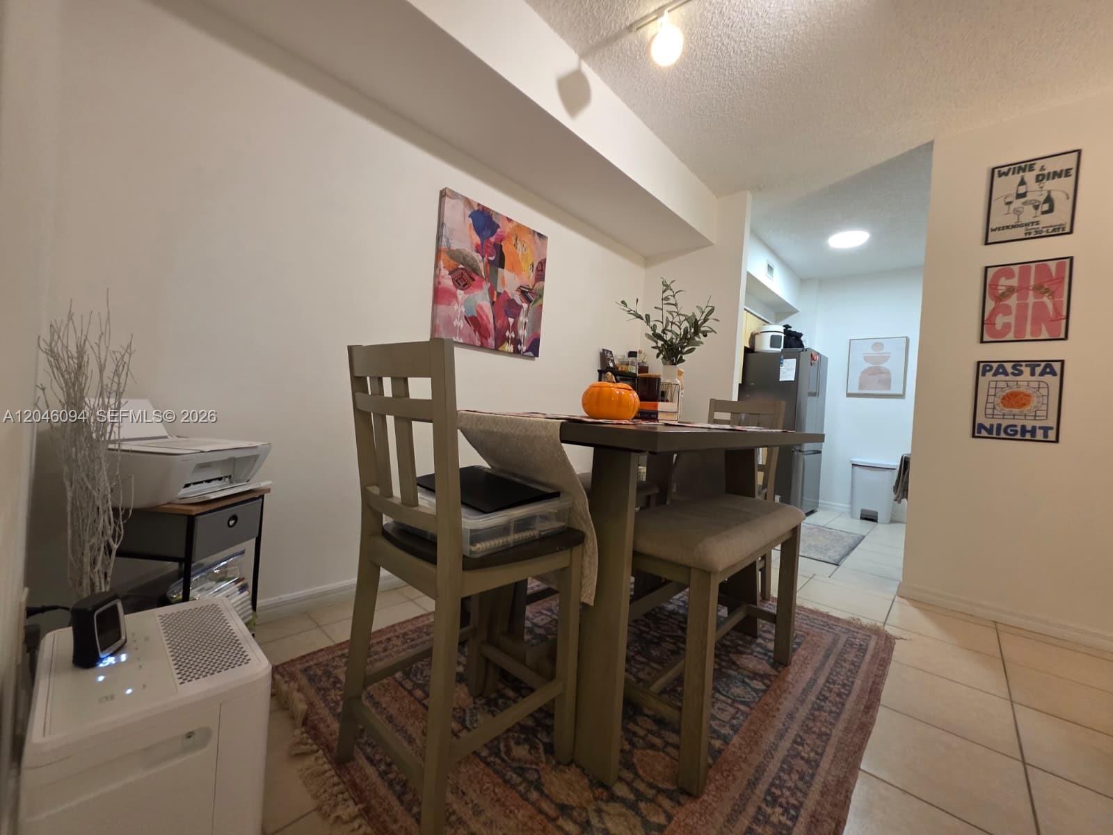 A dining area features a wooden table with chairs, a rug, and wall art — 2201 W Preserve Way # 208, Miramar FL 33025, MIRAMAR, FL