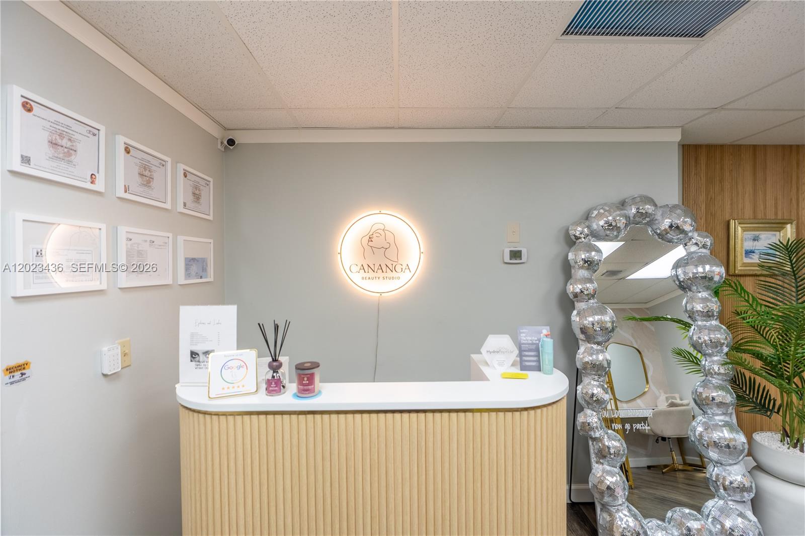 A reception area features a curved wooden desk, a glowing circular logo, and a disco-ball mirror — 1250 E Hallandale Beach Blvd, Hallandale Beach FL 33009, HALLANDALE BEACH, FL
