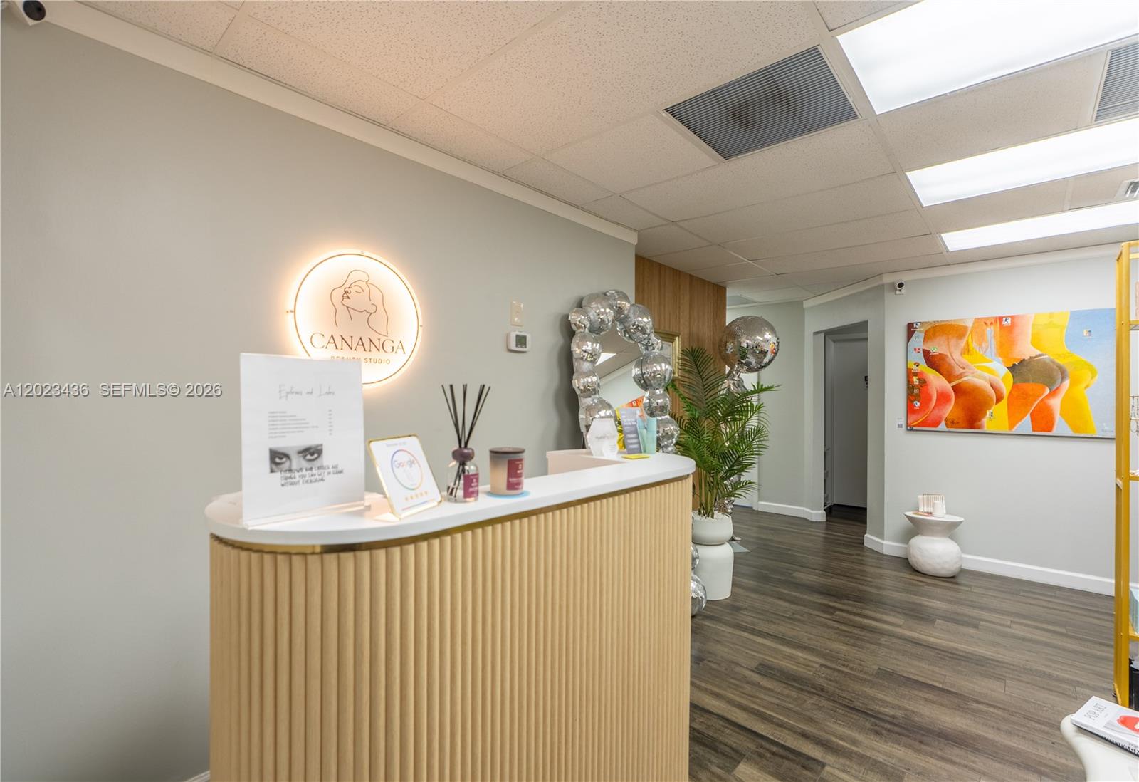 A reception area features a curved wooden desk, a glowing circular sign, and modern decor — 1250 E Hallandale Beach Blvd, Hallandale Beach FL 33009, HALLANDALE BEACH, FL