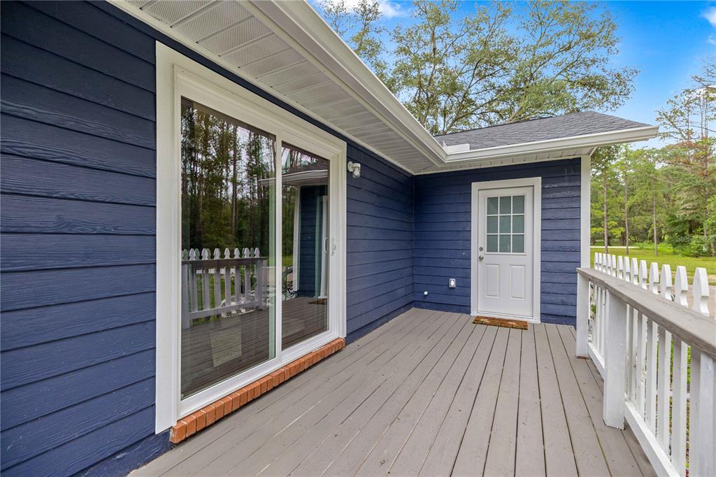 A blue-sided house exterior features a wooden deck, a sliding glass door, and a door — 13750 105 PLACE SW, DUNNELLON, FL