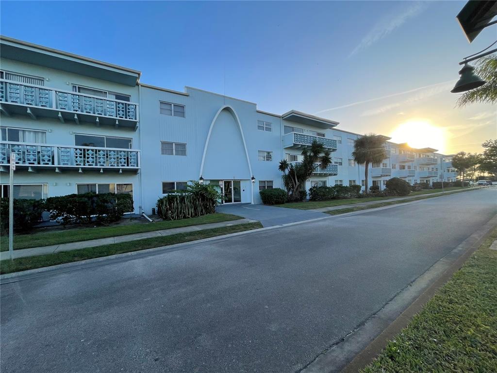 A multi-story, light blue apartment building features a prominent arched entryway and exterior balconies — 223 COLUMBIA DRIVE UNIT 211, CAPE CANAVERAL, FL