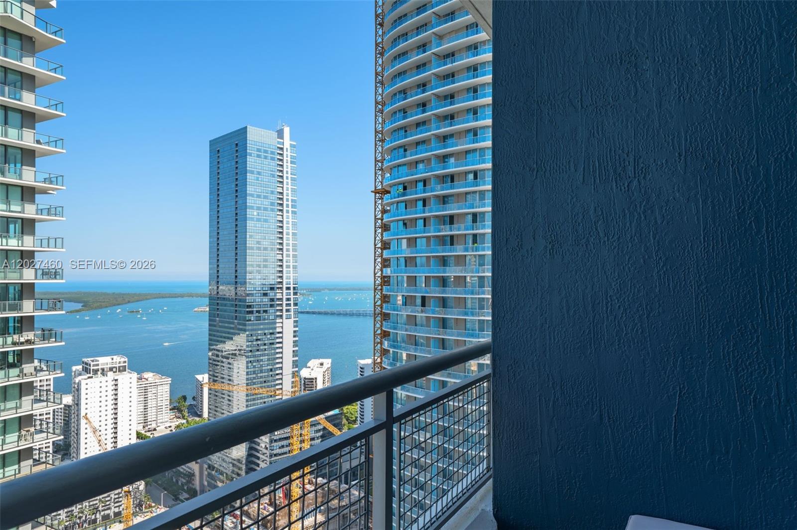 A high-rise balcony overlooks a bay with multiple skyscrapers and construction cranes — 60 SW 13th St # 4408, Miami FL 33130, MIAMI, FL