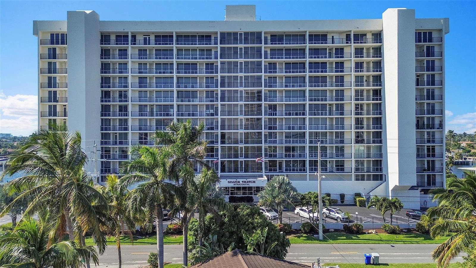 An exterior view of a multi-story residential building with balconies and palm trees in front — 521 N Riverside Drive # 707, Pompano Beach FL 33062, POMPANO BEACH, FL