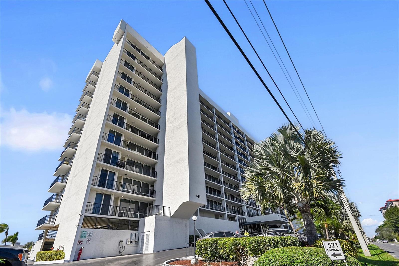 A low-angle exterior view of a tall, white multi-story apartment building with balconies — 521 N Riverside Drive # 707, Pompano Beach FL 33062, POMPANO BEACH, FL
