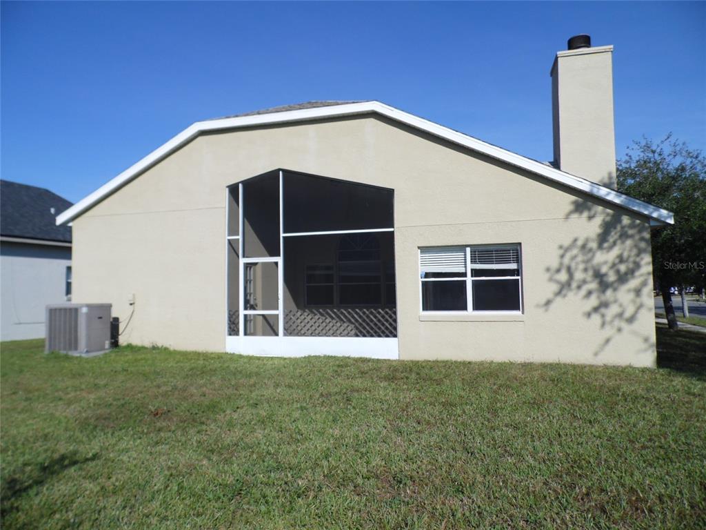 The rear exterior of a beige house features a screened-in porch and a chimney — 11020 FELTON COURT, ORLANDO, FL