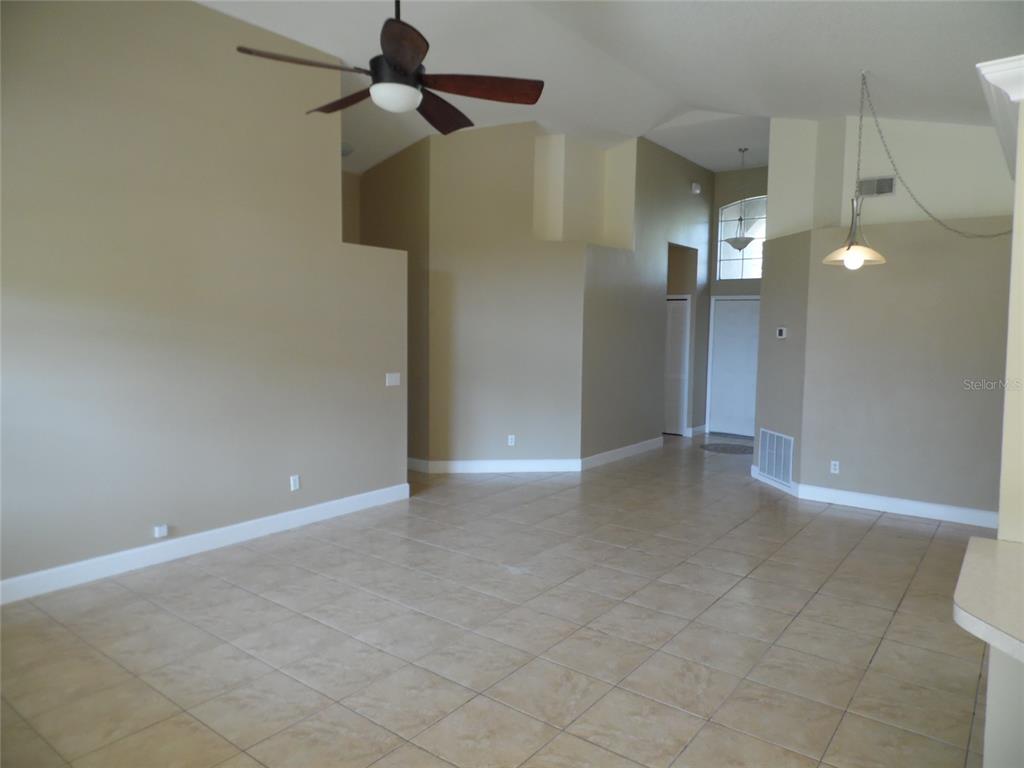 A spacious living area features beige walls, tile flooring, a ceiling fan, and vaulted ceilings — 11020 FELTON COURT, ORLANDO, FL