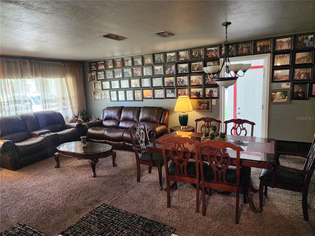 A living and dining area features brown leather furniture, a large photo gallery wall, and carpeting — 1317 MOSS LANE, COCOA, FL