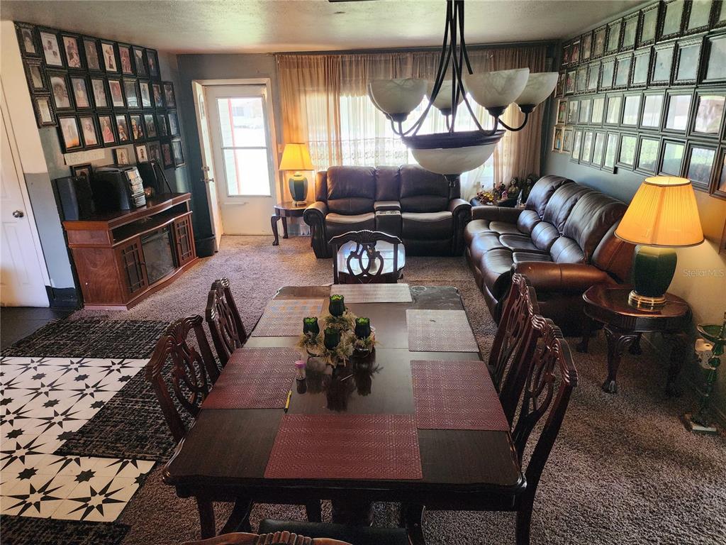 A dining area with a wooden table and chairs opens into a living room space — 1317 MOSS LANE, COCOA, FL