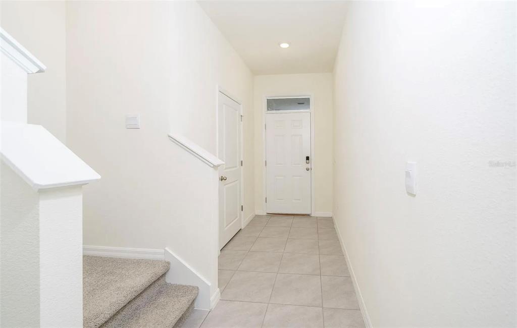 An entryway features a white front door, tiled flooring, and carpeted stairs leading upward — 1623 HUBBELL ROAD, WESLEY CHAPEL, FL