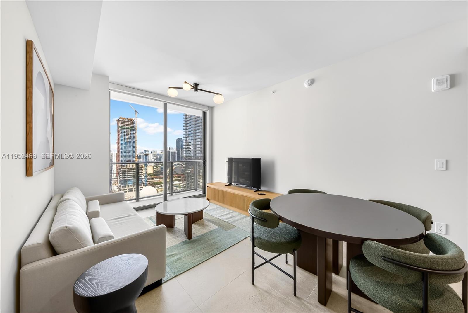 A modern living and dining area features floor-to-ceiling windows overlooking a city skyline — 11 NE 6 ST # 3210, Miami FL 33132, MIAMI, FL
