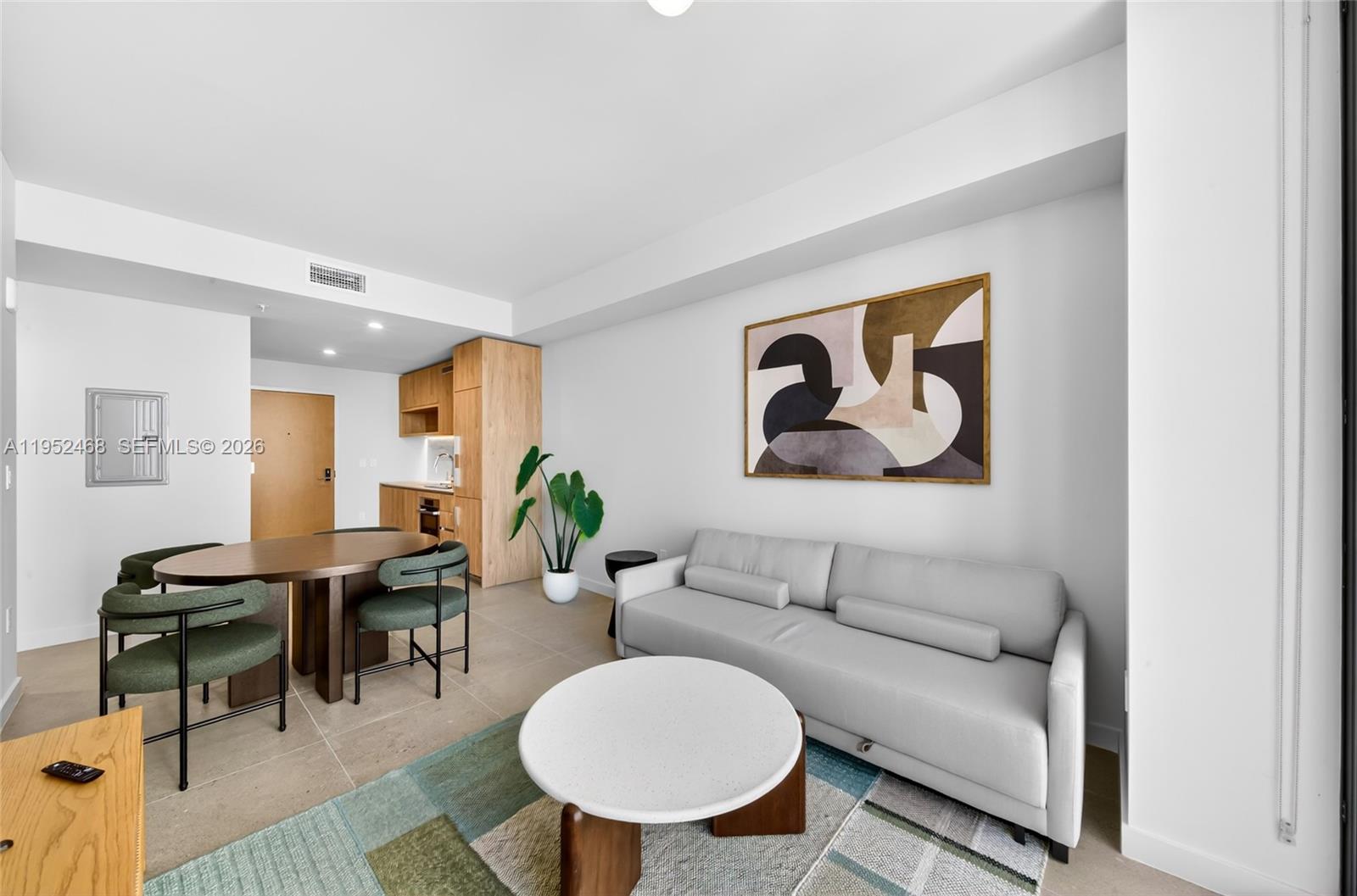 A modern living and dining area features a gray sofa, round coffee table, and table — 11 NE 6 ST # 3210, Miami FL 33132, MIAMI, FL