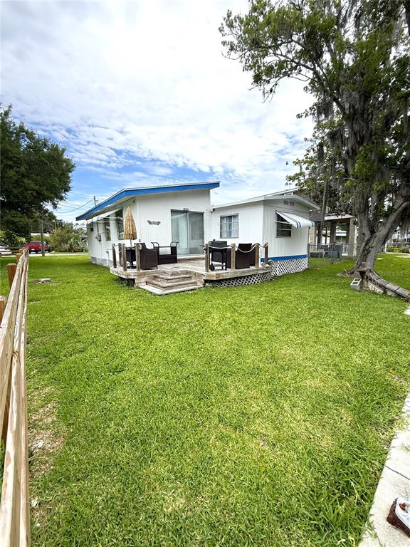 A white mobile home with a wooden deck sits on a grassy lawn — 10270 W GROTTO COURT, HOMOSASSA, FL