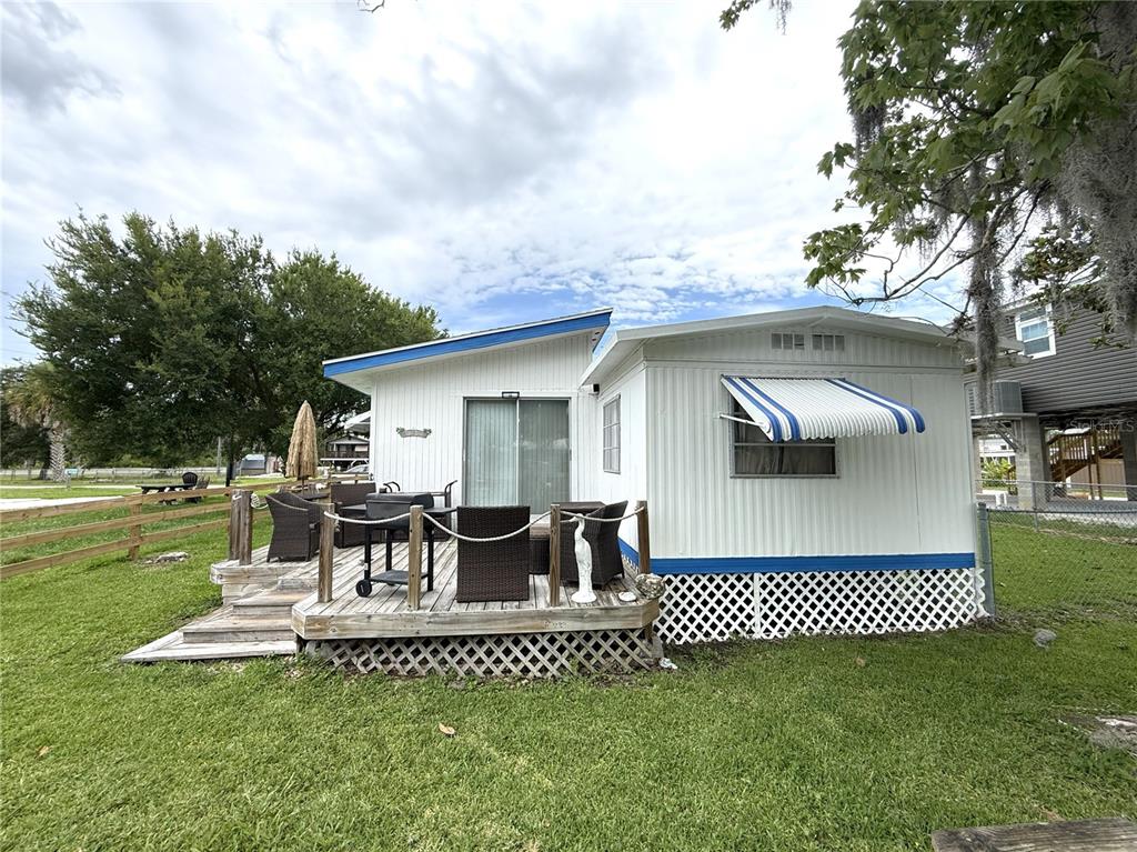 A white mobile home features a wooden deck with patio furniture and a grill — 10270 W GROTTO COURT, HOMOSASSA, FL