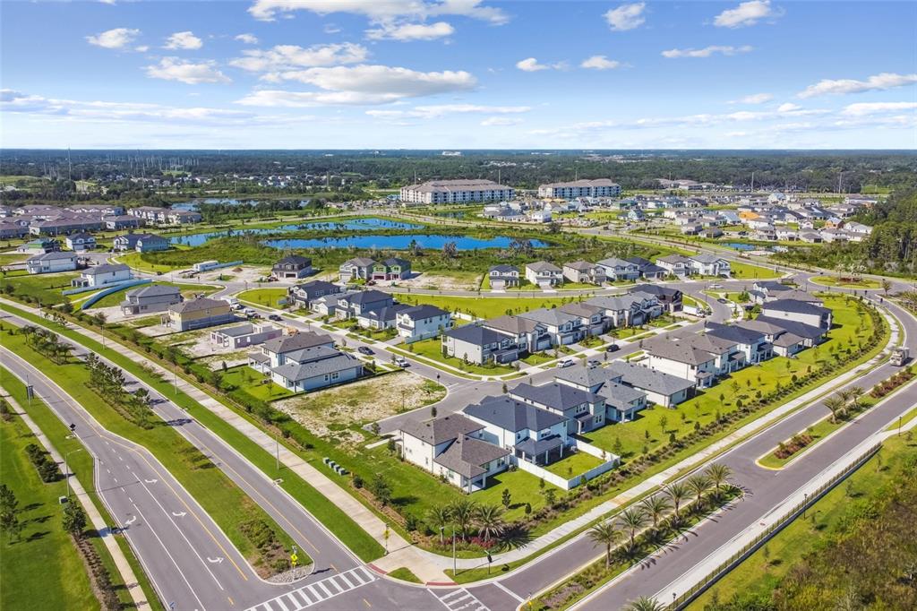 An aerial view shows a suburban neighborhood with single-family homes, roads, and a central pond — 5639 MAYDALE AVENUE, WESLEY CHAPEL, FL