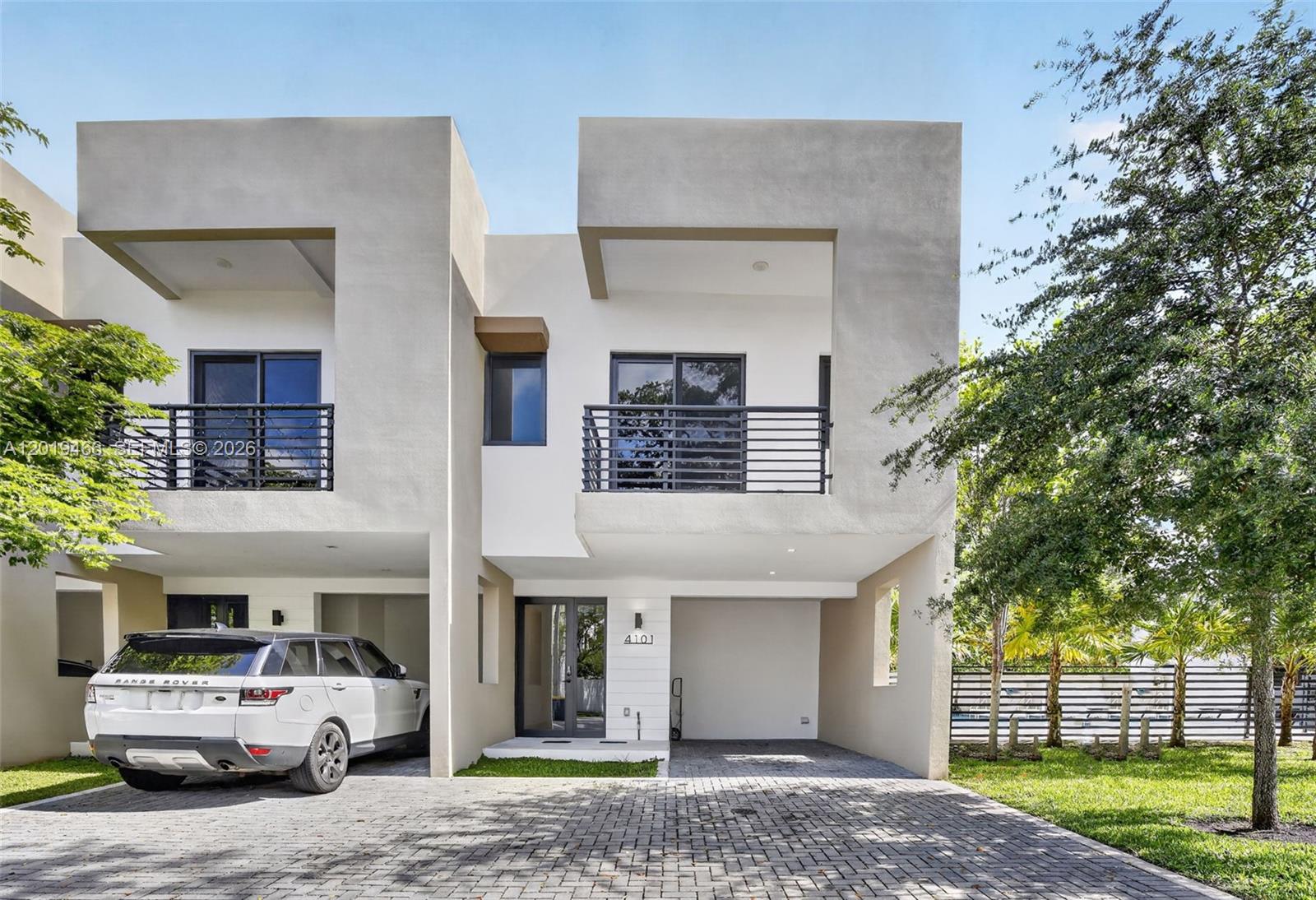 A modern two-story townhouse with a paved driveway, a white SUV, and a balcony — 4101 N Oak Pl, Dania Beach FL 33314, DANIA BEACH, FL