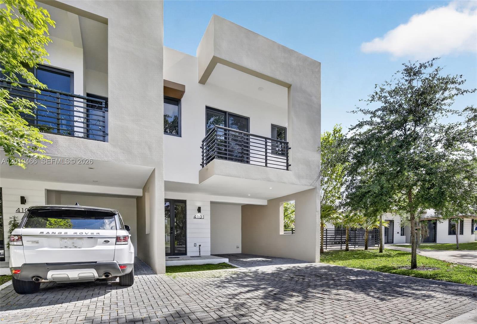 A modern two-story townhouse features a paved driveway, a covered carport, and a second-floor balcony — 4101 N Oak Pl, Dania Beach FL 33314, DANIA BEACH, FL