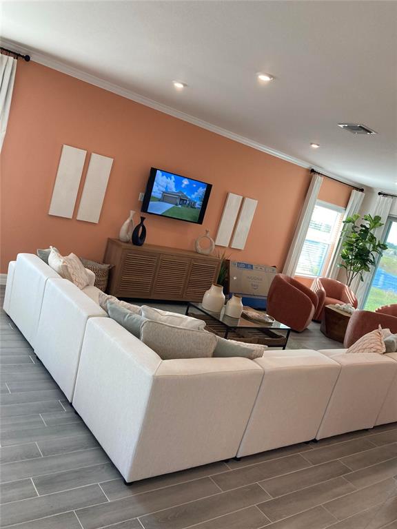 A living room features a large white sectional sofa, a wooden media console, and peach-colored walls — 25584 CALUSA DRIVE, PUNTA GORDA, FL