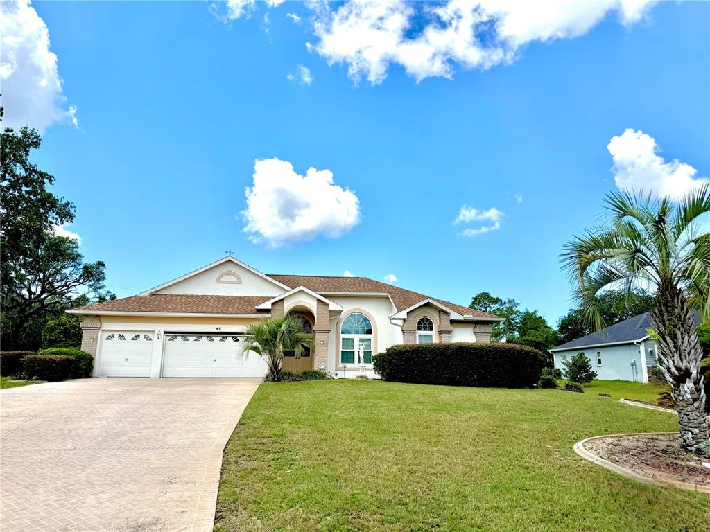 A single-story house with a beige exterior, a two-car garage, and a paved driveway — 48 N CRYSTAL MEADOW PATH, LECANTO, FL