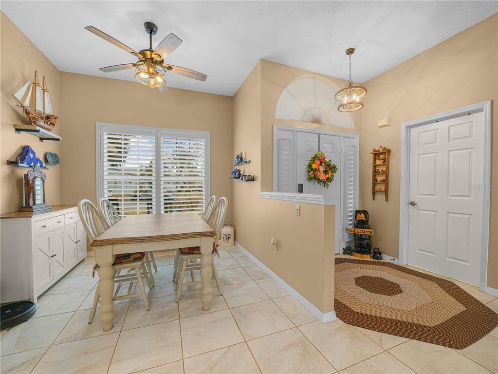 A dining area with tile floors, a wooden table, and an adjacent entryway with a door — 5888 SANDPIPERS DRIVE, LAKELAND, FL