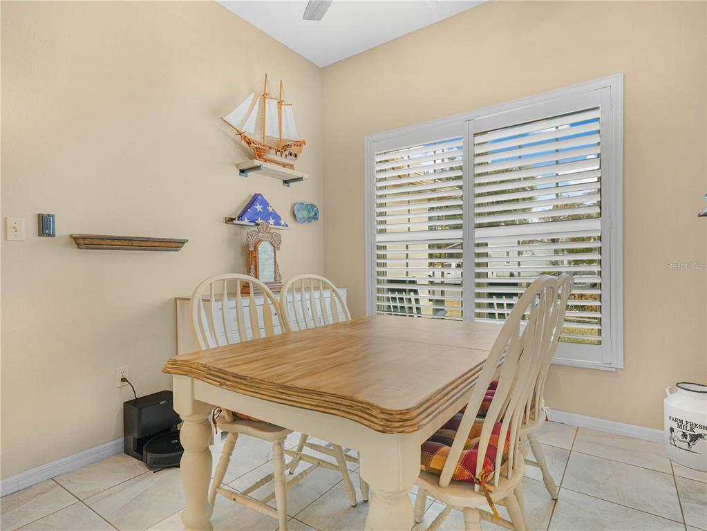 A dining area features a wooden table, white chairs, plantation shutters, and nautical wall decor — 5888 SANDPIPERS DRIVE, LAKELAND, FL