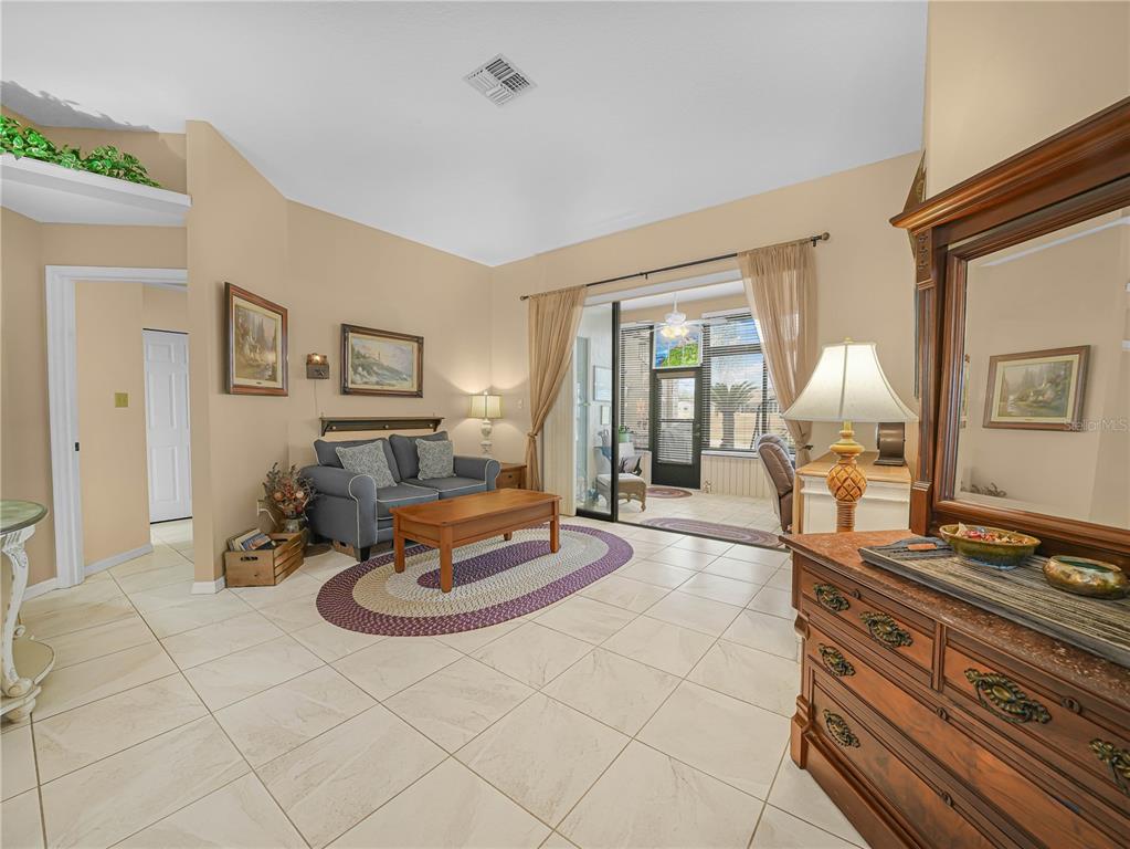 A living room with tile flooring, a small sofa, a coffee table, and a sunroom beyond — 5888 SANDPIPERS DRIVE, LAKELAND, FL