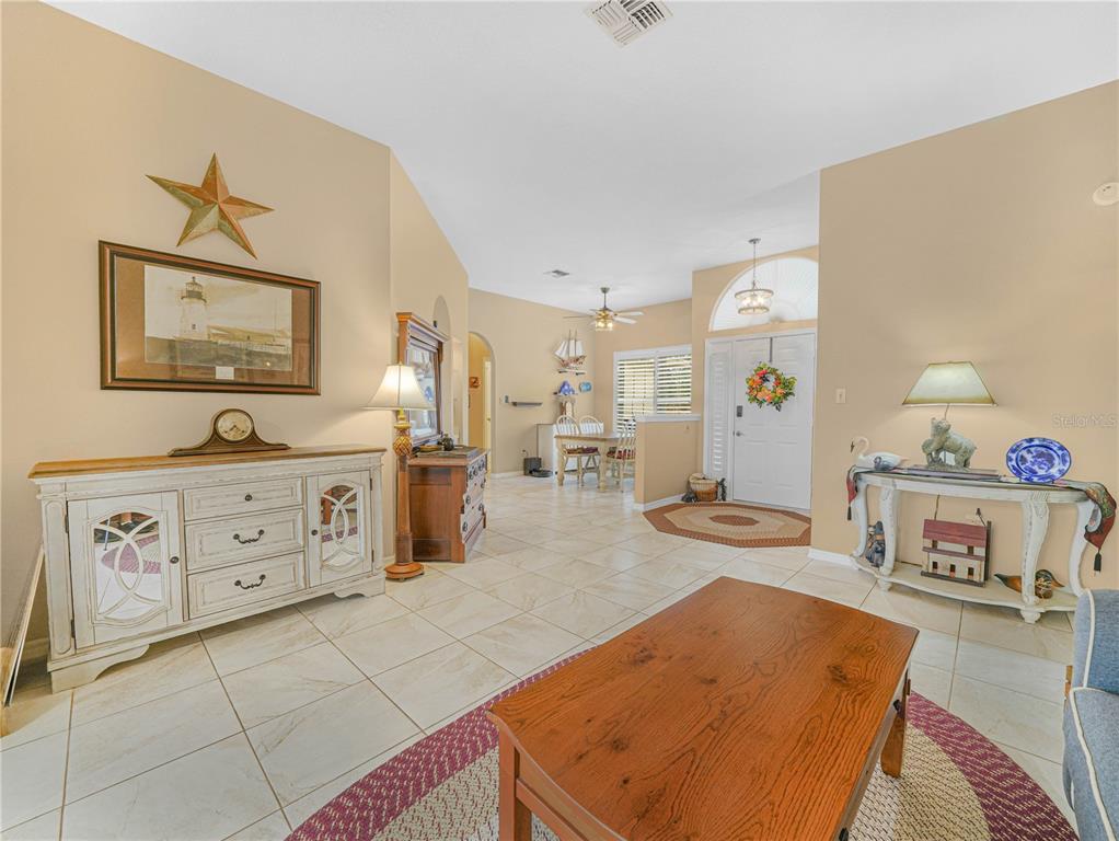 A living room with tile floors, a wooden coffee table, and a white entryway door — 5888 SANDPIPERS DRIVE, LAKELAND, FL