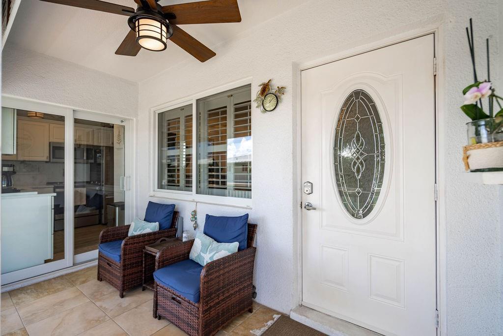A covered patio features two wicker chairs, a ceiling fan, and a white front door — 2100 NE 38th Street # 229, Lighthouse Point FL 33064, LIGHTHOUSE POINT, FL