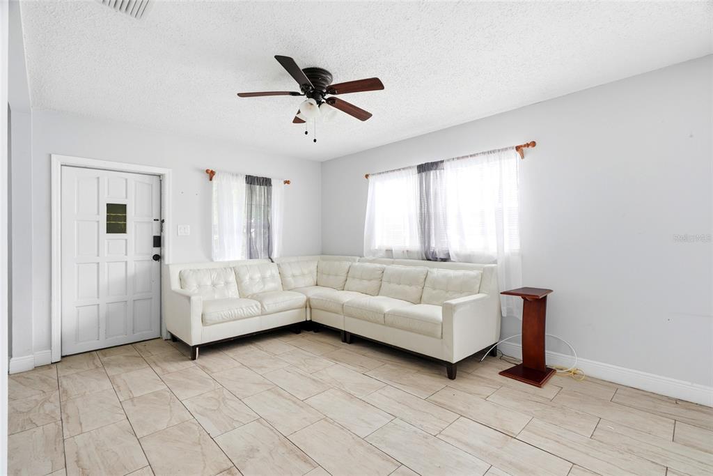 A living room features a white sectional sofa, tile flooring, and a ceiling fan — 2430 N RAMONA CIRCLE, TAMPA, FL