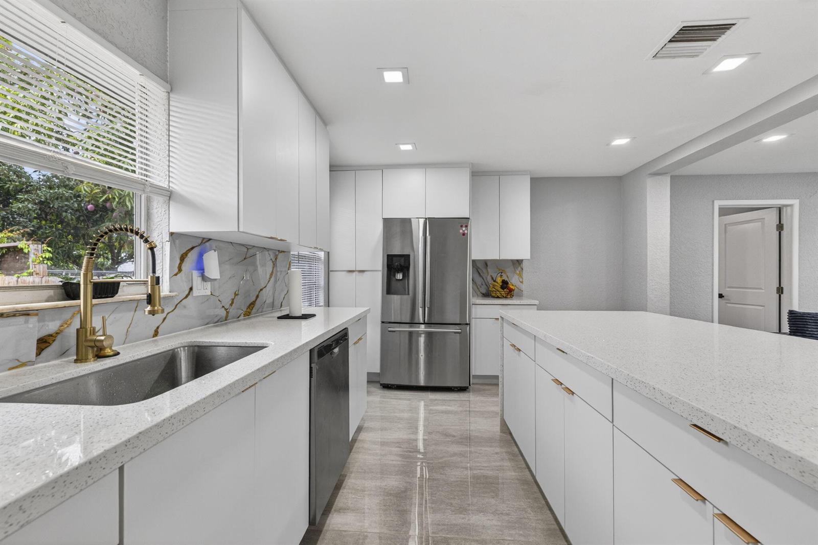 A modern kitchen features white cabinets, quartz countertops, a stainless steel refrigerator, and gold hardware — 800 NW 6th Avenue, Pompano Beach FL 33060, POMPANO BEACH, FL