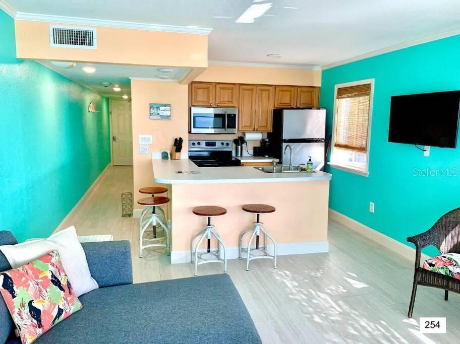 A kitchen with light-colored cabinets and a breakfast bar overlooks a living area — 2506 N ROCKY POINT DRIVE UNIT 254, TAMPA, FL