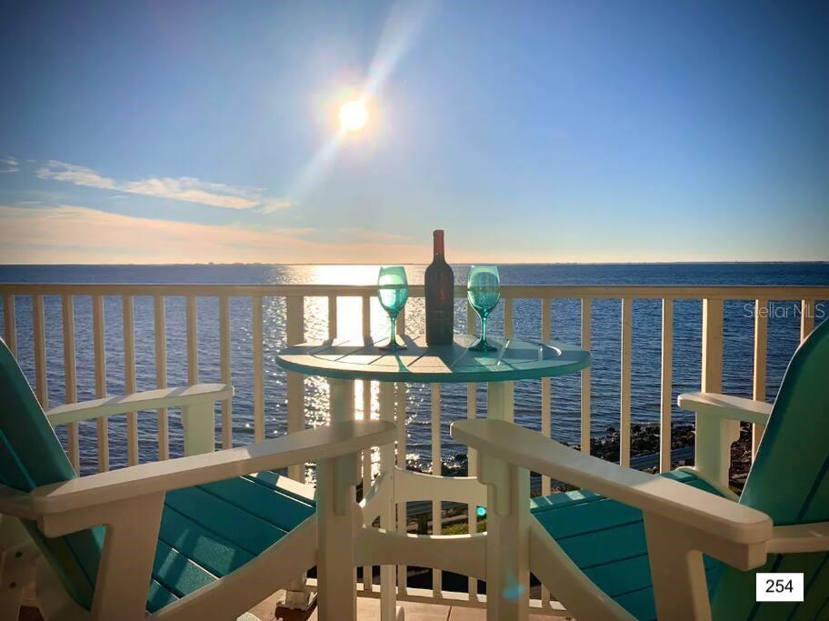 A balcony with two chairs and a table holding a wine bottle and two glasses — 2506 N ROCKY POINT DRIVE UNIT 254, TAMPA, FL