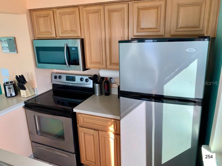 A kitchen features stainless steel appliances, light wood cabinets, and light-colored countertops — 2506 N ROCKY POINT DRIVE UNIT 254, TAMPA, FL