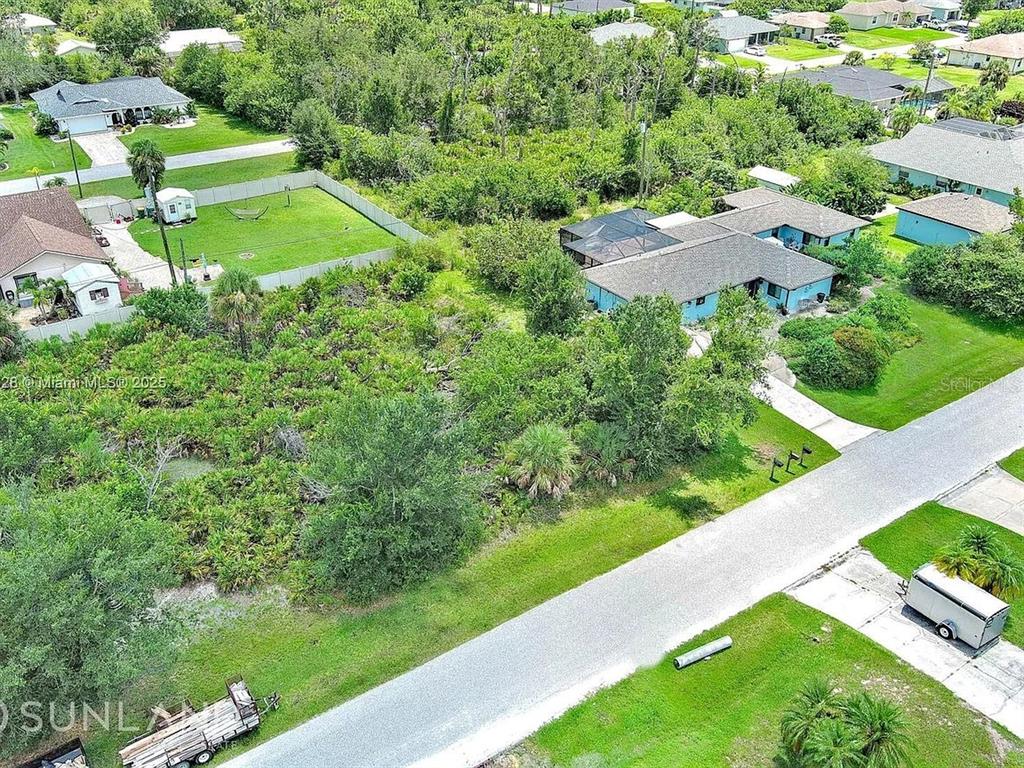 An aerial view shows a blue house with a pool cage surrounded by dense vegetation — 7296 SKYCREST STREET, ENGLEWOOD, FL