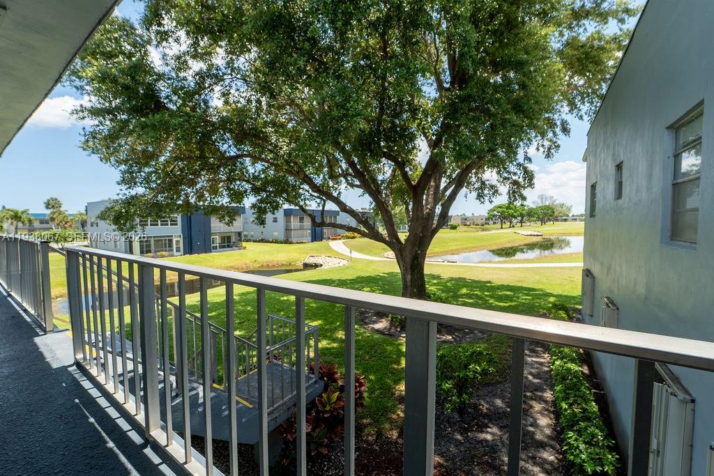 A view from a balcony overlooking a grassy lawn, a pond, and residential buildings — 938 Normandy T # T938, Delray Beach FL 33484, DELRAY BEACH, FL
