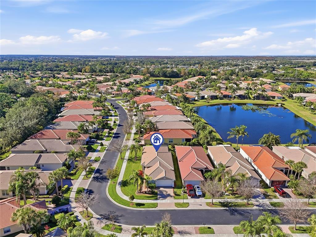 An aerial view shows a suburban neighborhood with houses, a lake, and palm trees — 15767 CRYSTAL WATERS DRIVE, WIMAUMA, FL