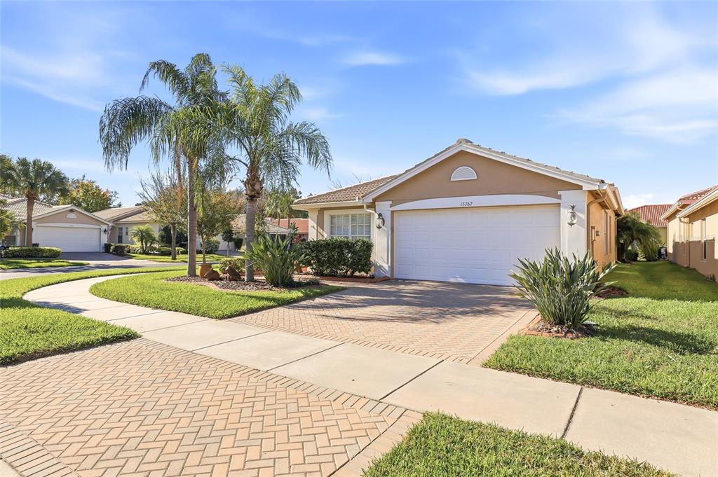 A single-story house with a tan exterior, a two-car garage, and a brick-paved driveway — 15767 CRYSTAL WATERS DRIVE, WIMAUMA, FL