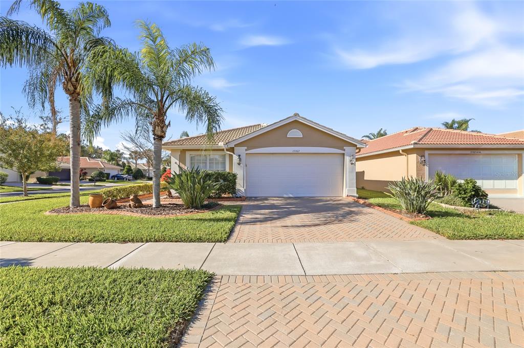 A single-story suburban house with a two-car garage, paved driveway, and two palm trees — 15767 CRYSTAL WATERS DRIVE, WIMAUMA, FL