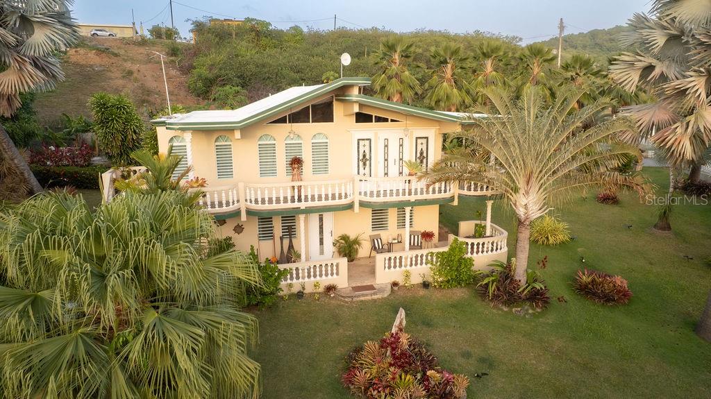 An aerial view of a two-story yellow house with a balcony and surrounding palm trees — 393 MONTE CARMELO, VIEQUES, PR