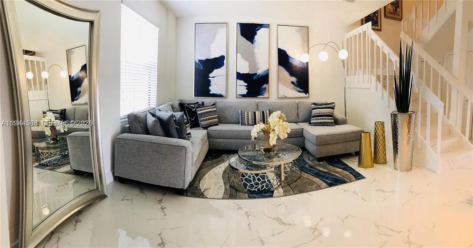 A living room features a grey sectional sofa, a round coffee table, and marble flooring — 10162 SW 228th Ter, Miami FL 33190, MIAMI, FL