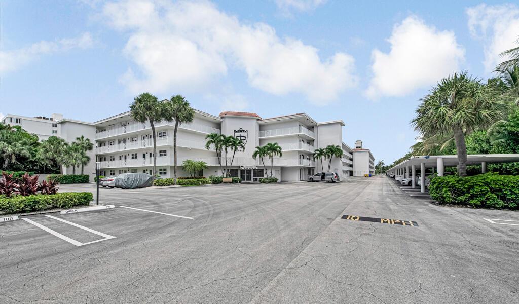A multi-story apartment building features a large parking lot with covered spaces and palm trees — 1910 S Ocean Boulevard # 112, Delray Beach FL 33483, DELRAY BEACH, FL