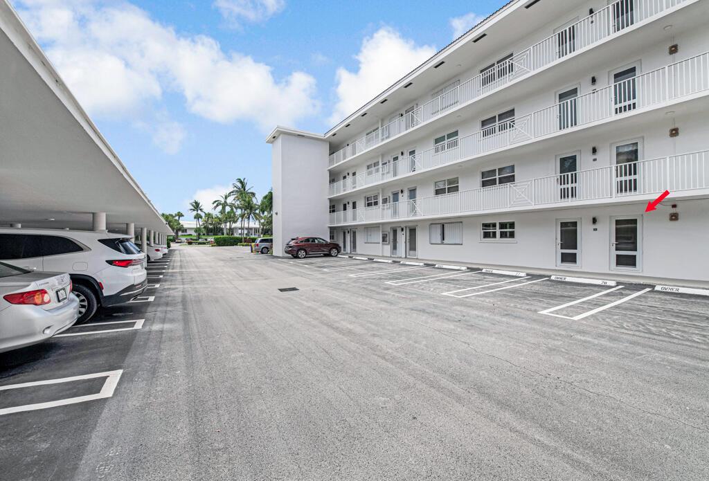 A multi-story white apartment building features a parking lot with covered and uncovered spaces — 1910 S Ocean Boulevard # 112, Delray Beach FL 33483, DELRAY BEACH, FL