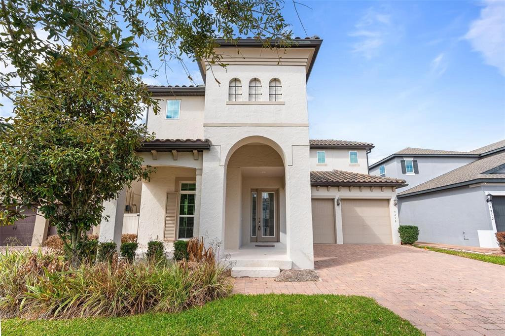 A two-story stucco house with a tile roof, arched entryway, and a paved driveway — 9218 HOLLISTON CREEK PLACE, WINTER GARDEN, FL