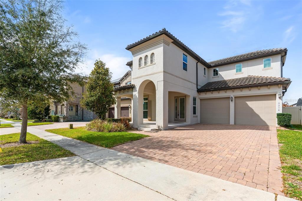 A two-story stucco house with a tile roof, arched entryway, and a paved driveway — 9218 HOLLISTON CREEK PLACE, WINTER GARDEN, FL