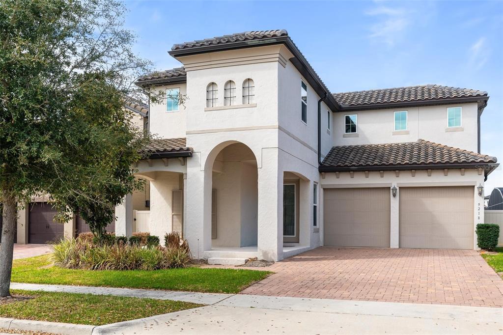 A two-story stucco house features a tiled roof, arched entryway, and a two-car garage — 9218 HOLLISTON CREEK PLACE, WINTER GARDEN, FL