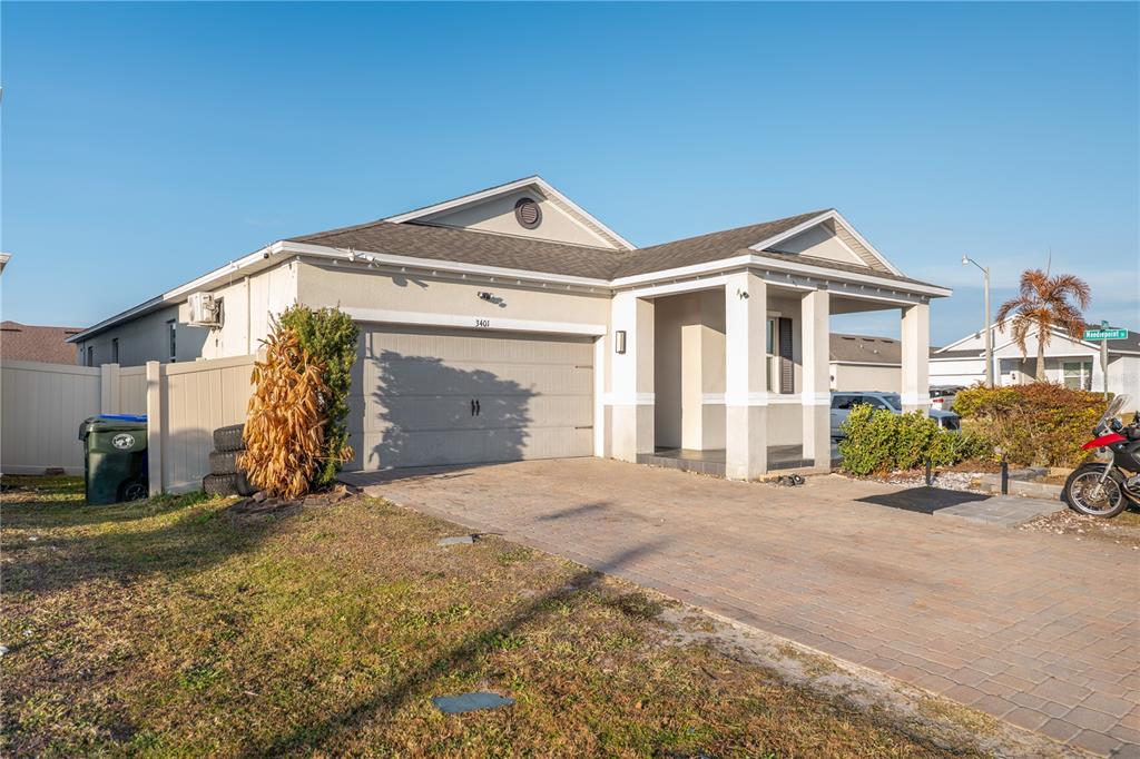 A single-story house with a gray garage, a covered entryway, and a paved driveway — 3401 CANVAS STREET, KISSIMMEE, FL