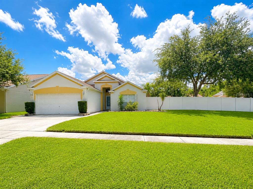 A single-story house with a white exterior, yellow accents, a two-car garage, and a lawn — 4201 PINE ISLE DRIVE, LUTZ, FL