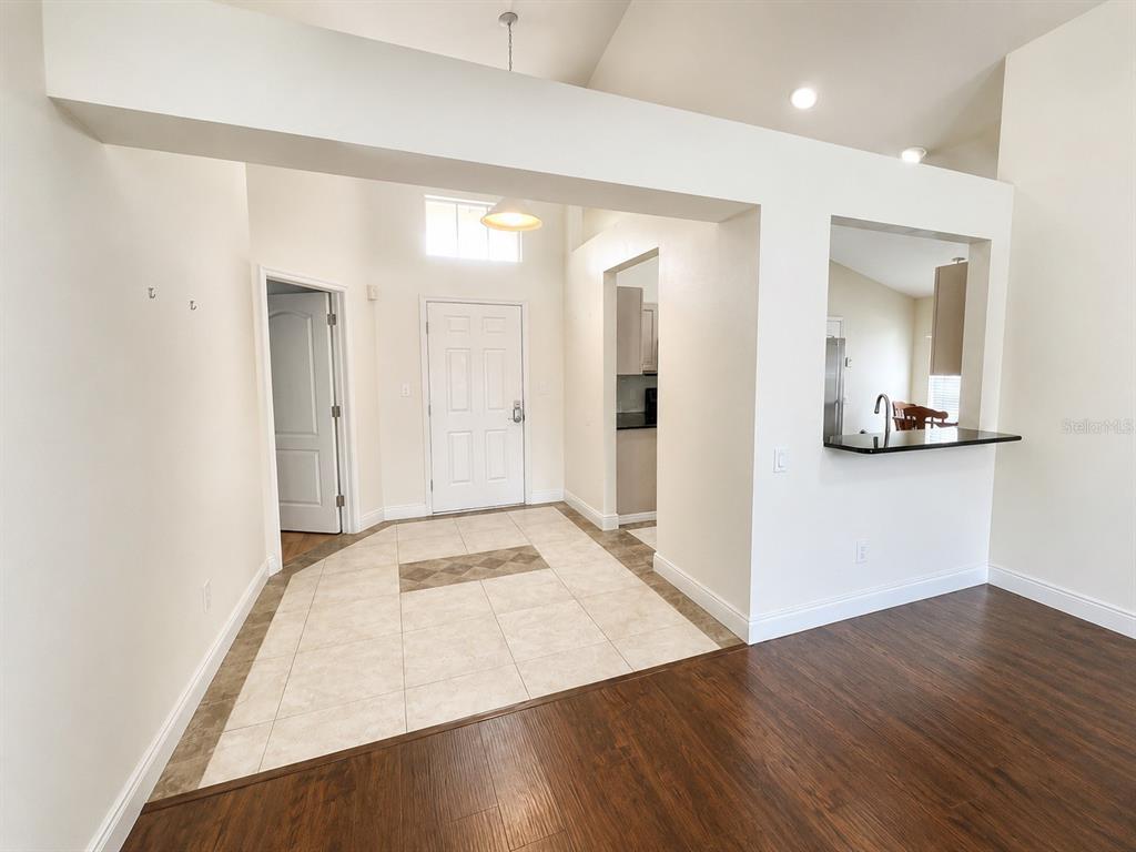 An entryway with tiled flooring leads to a front door, adjacent to a kitchen pass-through — 4201 PINE ISLE DRIVE, LUTZ, FL