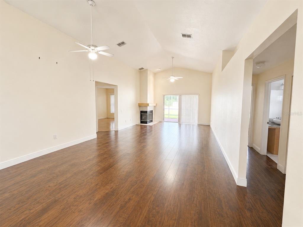 A spacious living room with vaulted ceilings, dark wood flooring, and a corner fireplace — 4201 PINE ISLE DRIVE, LUTZ, FL
