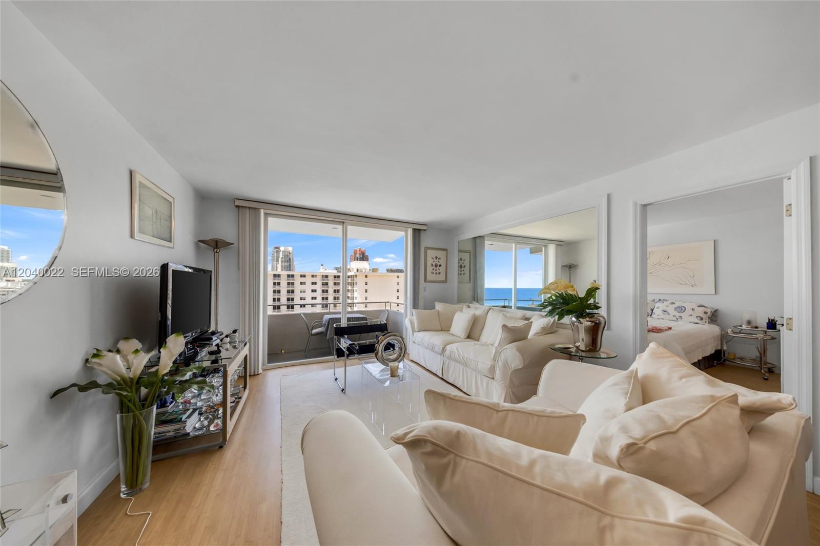 A bright living room features white sofas, a glass coffee table, and a balcony view — 465 Ocean Dr # 1009, Miami Beach FL 33139, MIAMI BEACH, FL