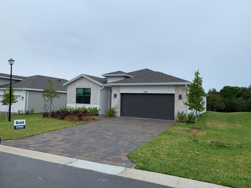 A single-story house with a stone facade, a dark garage door, and a paved driveway — 1949 NE Ocean Dunes Drive, Jensen Beach FL 34957, JENSEN BEACH, FL